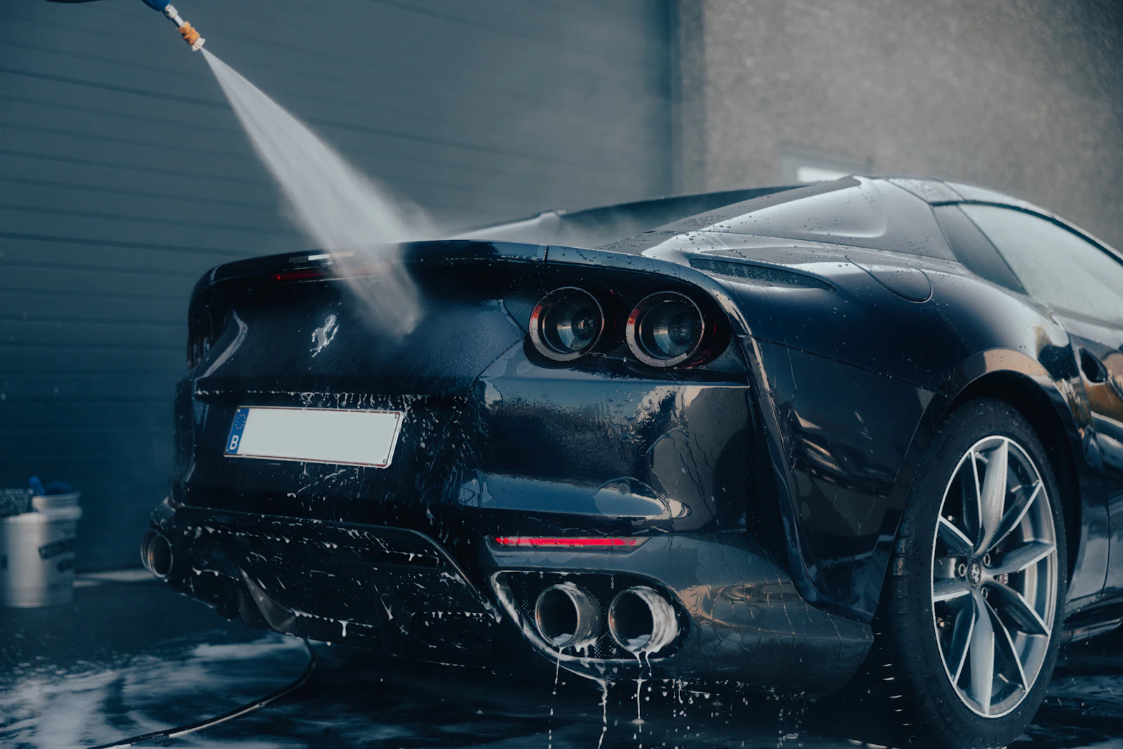 A car being cleaned with a pressure washer